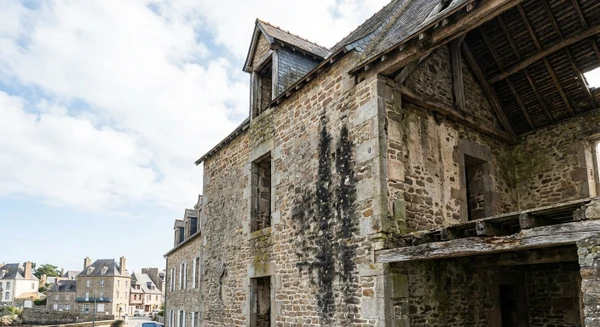 Photographie r&eacute;aliste d'une maison ou d'un b&acirc;timent ancien montrant des signes d'humidit&eacute;, de moisissures ou de dommages structurels aux bois (charpente visible, fa&ccedil;ade ab&icirc;m&eacute;e), illustrant le contexte des interventions de r&eacute;novation et traitement du b&acirc;ti men&eacute;es par 35 ATM dans son rayon d'action. L'image doit montrer un b&acirc;timent typique de la r&eacute;gion bretonne en &eacute;tat de d&eacute;gradation, repr&eacute;sentatif des probl&eacute;matiques trait&eacute;es (humidit&eacute;, insectes xylophages, &eacute;tat de la couverture).