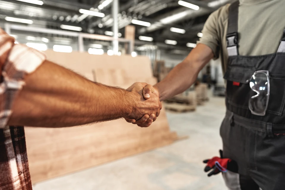 Chantier extérieur de traitement du bois avec ouvrier en gilet haute visibilité opérant une déchiqueteuse industrielle rouge