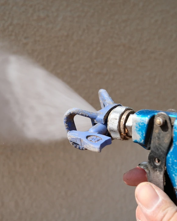 Photographie réaliste d'un mur intérieur résidentiel présentant des signes visibles d'humidité : taches d'humidité, décollement de peinture, moisissures superficielles et légère efflorescence saline (salpêtre) sur la surface murale inférieure. L'image doit montrer clairement la dégradation causée par l'humidité, dans une pièce d'habitation ordinaire avec un éclairage naturel ou ambiant professionnel.