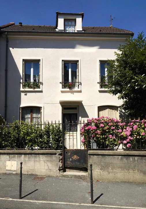 Façade de maison en pierre avec fenêtres à la française, mur végétalisé de lierre aux feuillages verts et rougeâtres